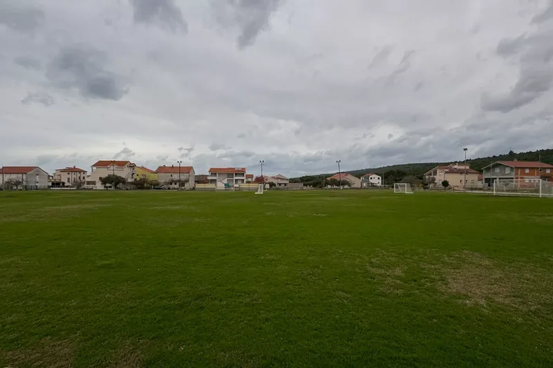 Nogometno igralište s kućama naselja u pozadini