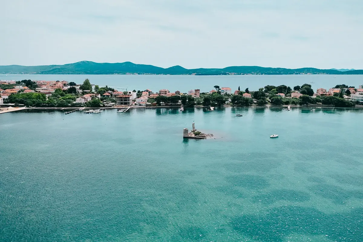 Zračni prikaz zaljeva s ostacima utvrde na otočiću i naseljem uz obalu